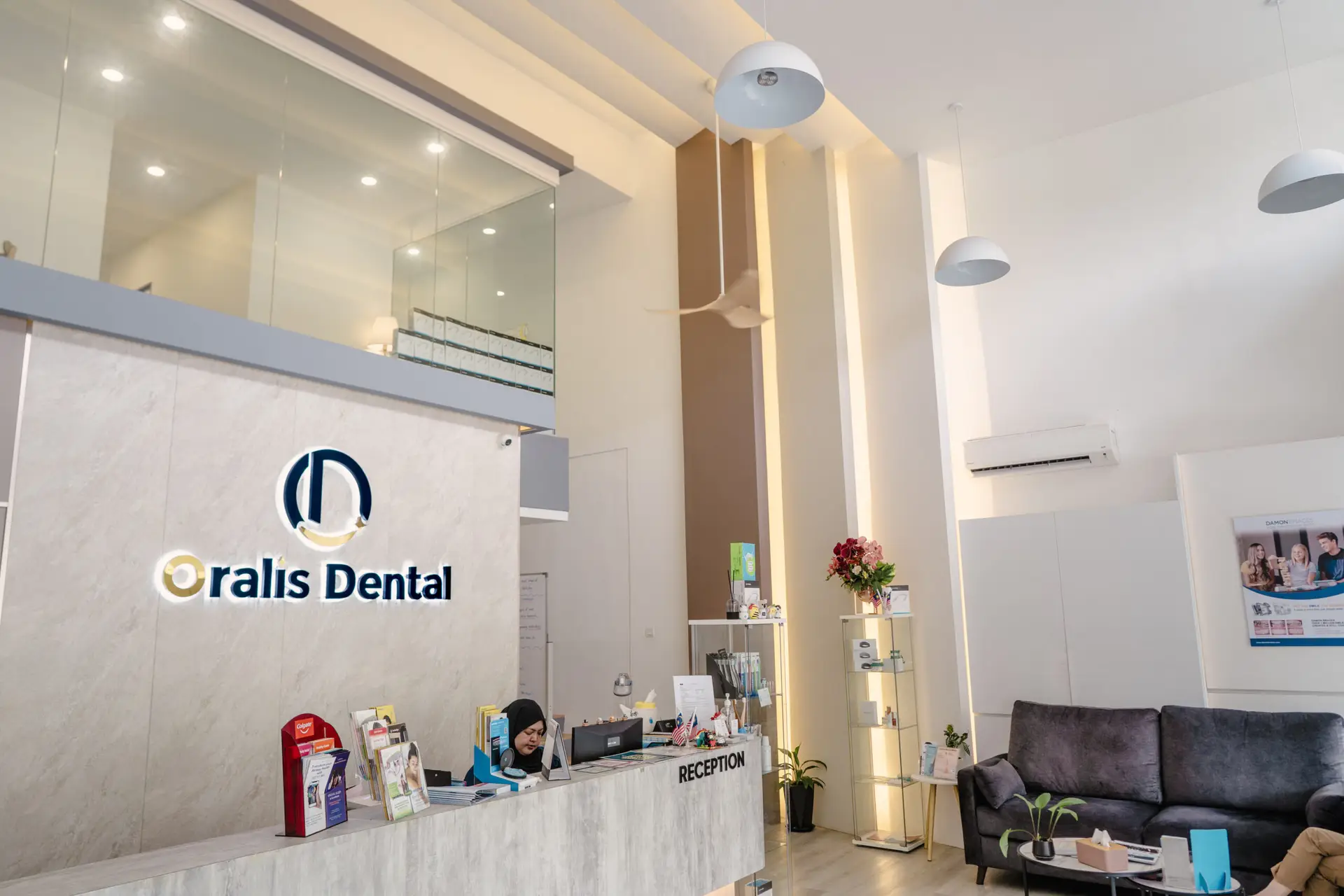 Reception desk at Oralis Dental Petaling Jaya with seated staff, brochures, and a welcoming modern interior.